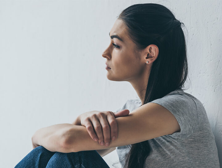 Woman leaning against wall thinking